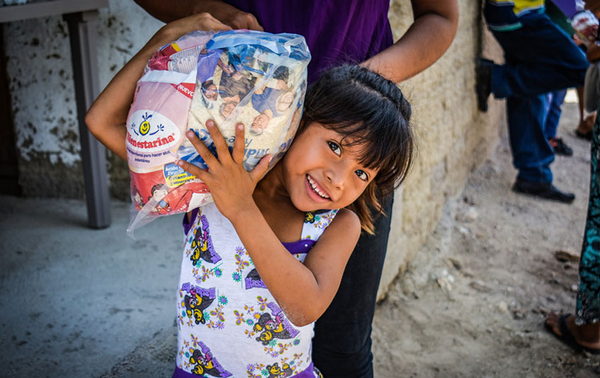 a girl holding a bag with an FMSC MannaPack meal bag inside it