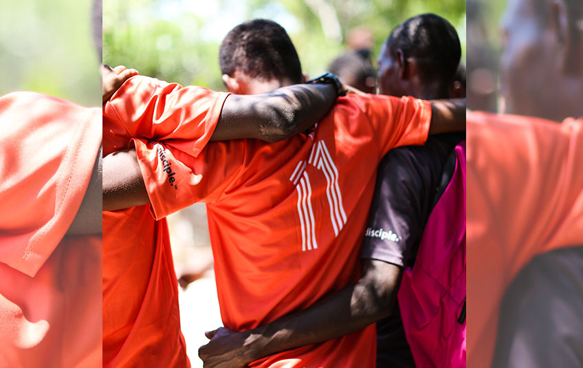 three Haitian men in soccer jerseys