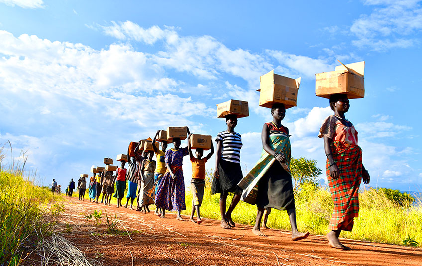 A group of people carrying boxes of FMSC food on their heads