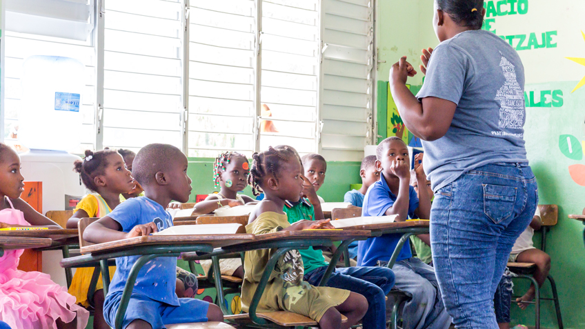 A woman teaches a classroom of kids in the Dominican Republic as part FMSC's feeding programs