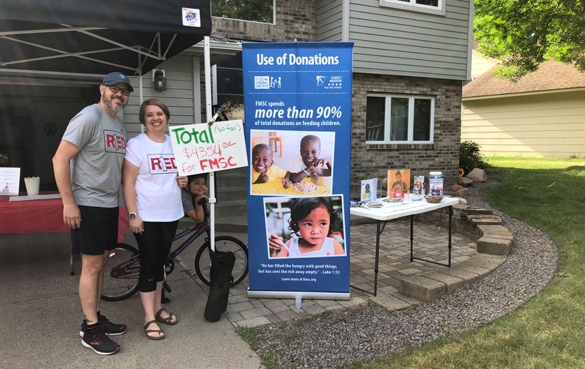 A man and woman stand next to an FMSC fundraising sign