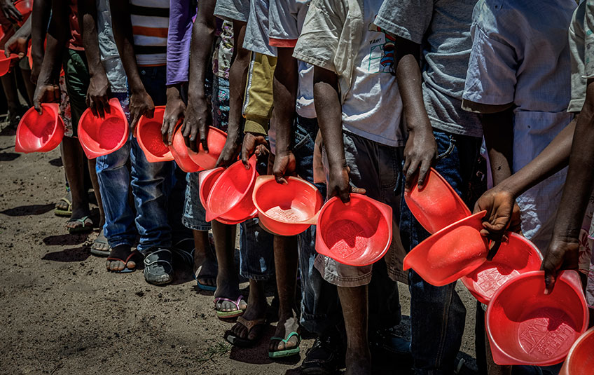 A line of children with empty bowls waits to receive FMSC food