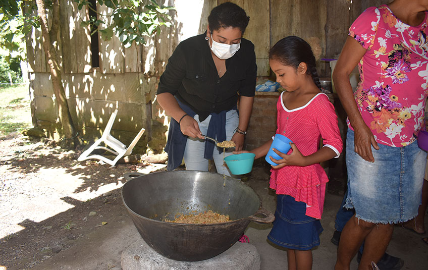 A woman spoons FMSC food into a girl's bowl