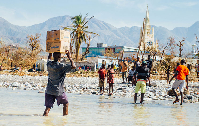a group carrying MannaPack boxes across a creek in Haiti