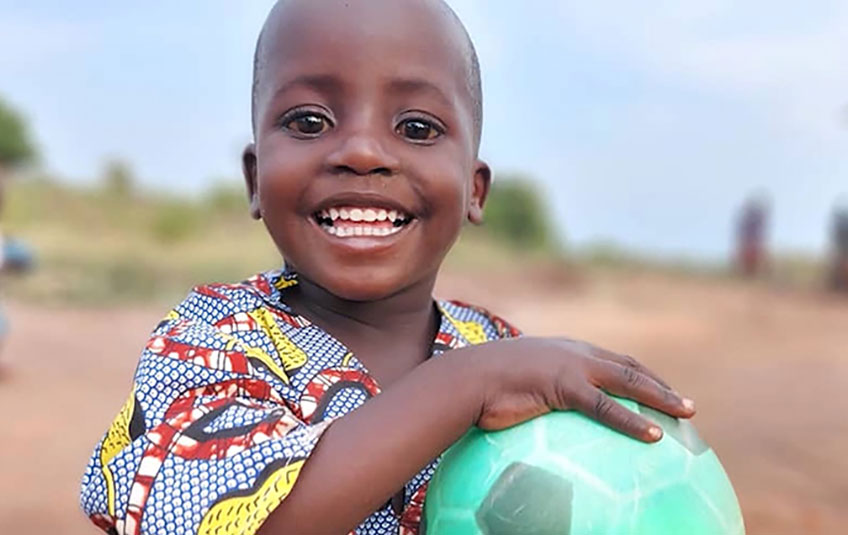 A Ugandan boy holding a green soccer ball