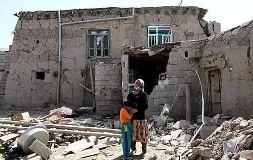 A woman and boy stand outside a destroyed building following Afghanistan earthquake