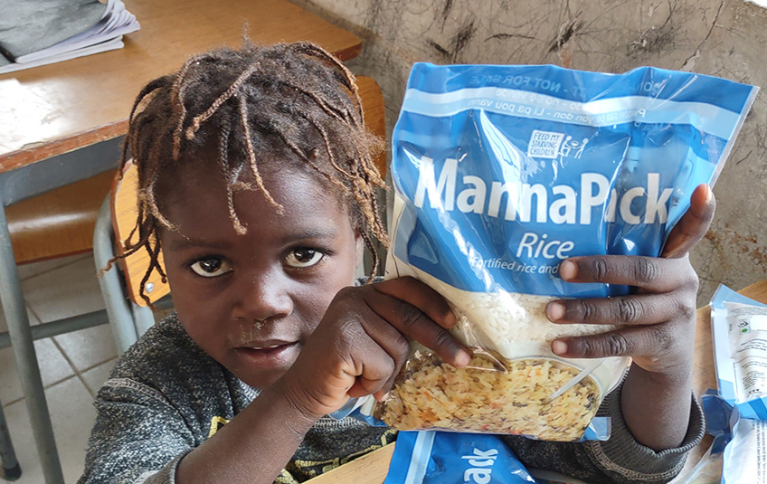 A malnourished child in Angola holding a bag of MannaPack Rice