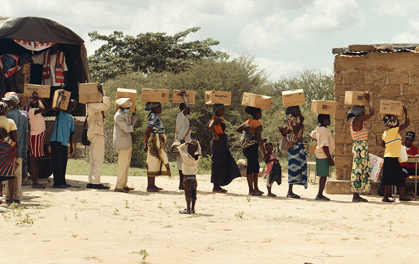 People standing in line carrying FMSC food boxes in Angola