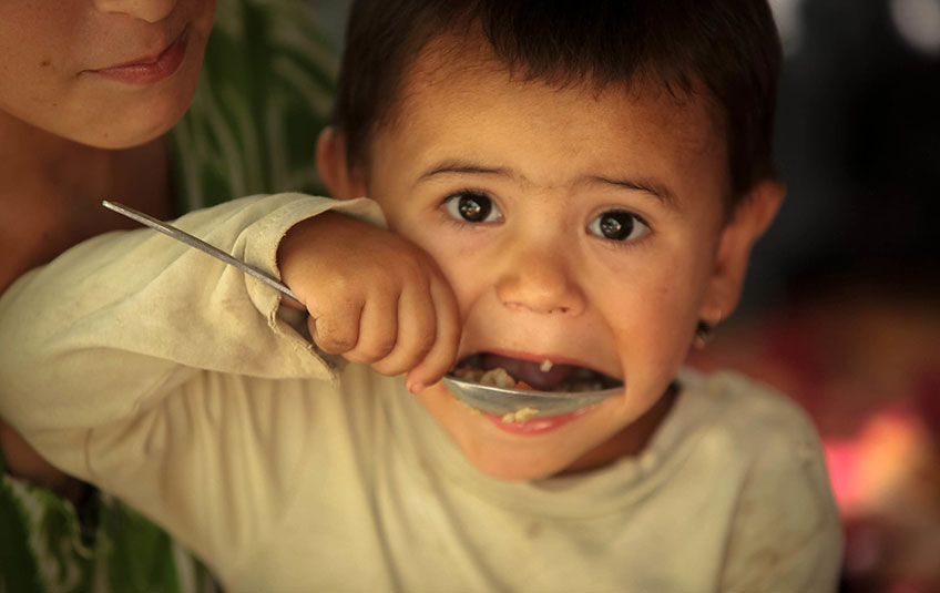 a boy spoons FMSC food into his mouth