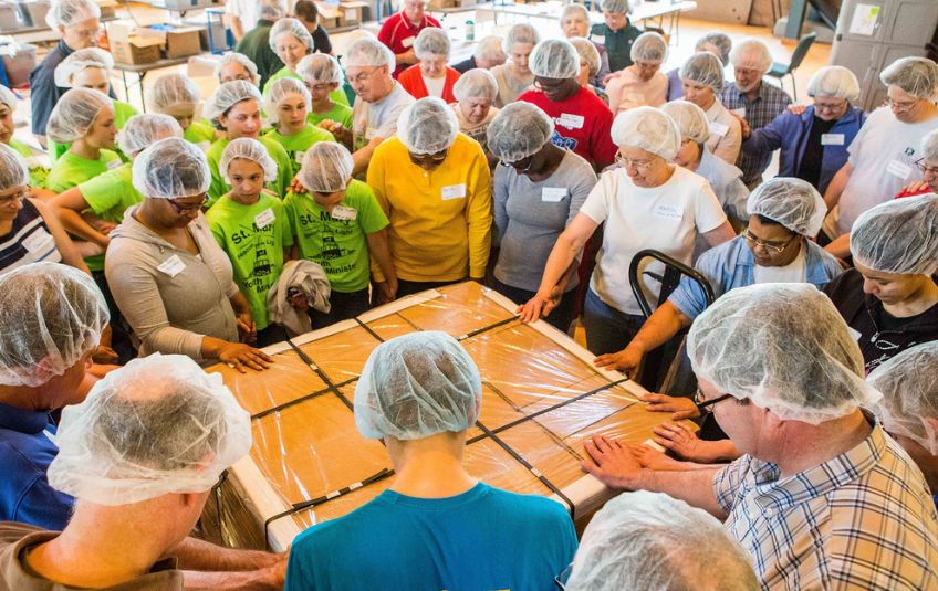 FMSC volunteers pray over a pallet of food boxes