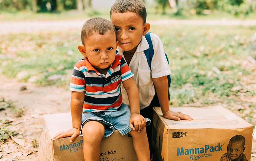 Two boys sitting on FMSC food boxes in Honduras