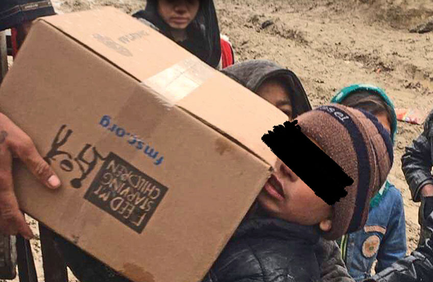 Boy receiving box of FMSC food in sensitive country