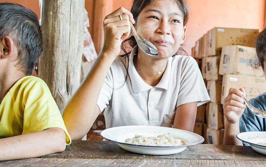 Girl eating MannaPack meal in Asia