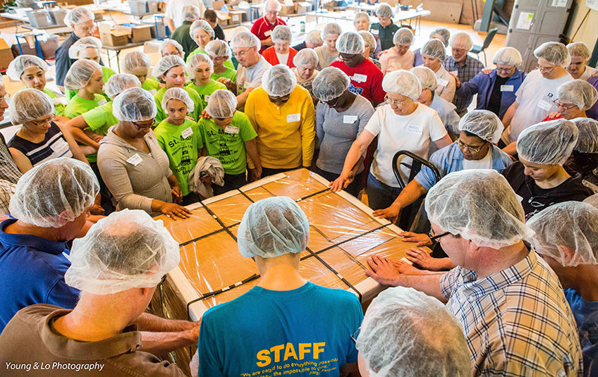 volunteers pray over a pallet of FMSC meals