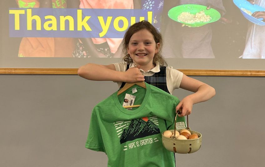 Eloise holding up her basket of eggs that helped her raise $106 and her thank-you gift t-shirt. 