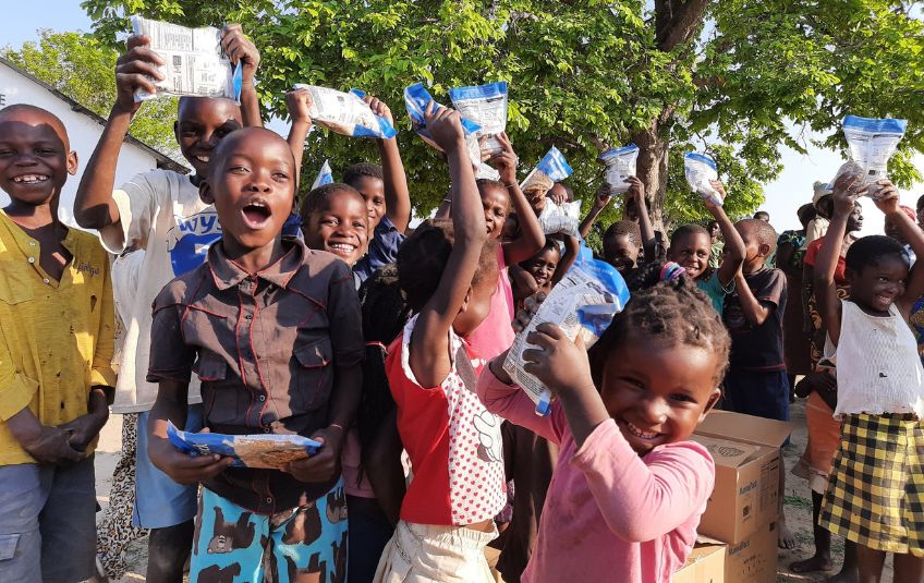 Kids in Zambia happy and holding MannaPack Meals.