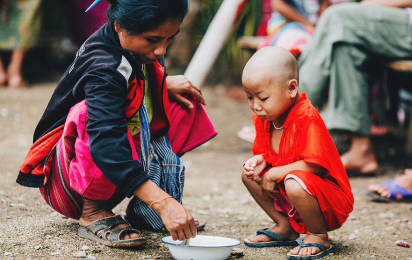 a woman feeding a child in Thailand