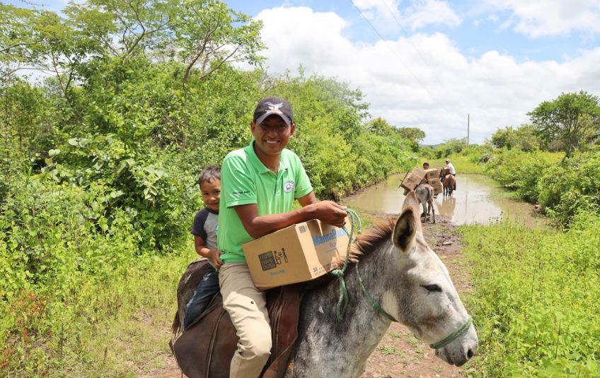 Man and child with MannaPack box on donkey. 