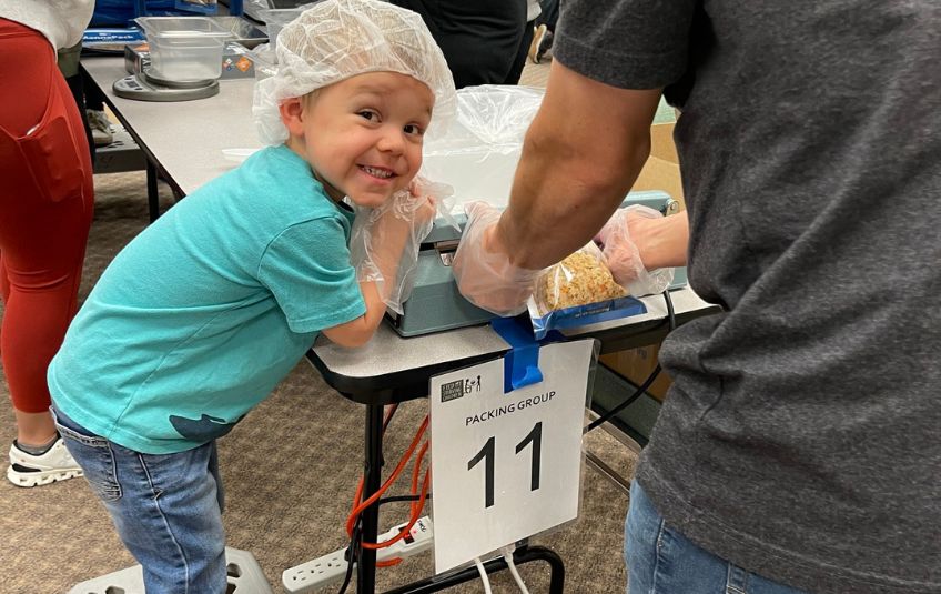 Young boy helping seal bags while volunteering at FMSC.