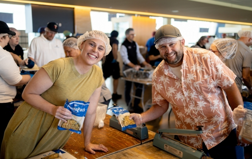 woman and man volunteers in hairnets with bags of MannaPack Rice