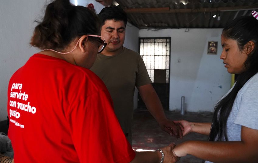 Bruno, his wife and a volunteer praying over their MannaPack meals.