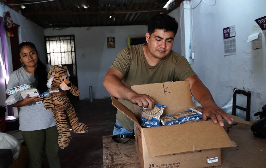 Bruno opening his box of MannaPack Rice as his wife watches.