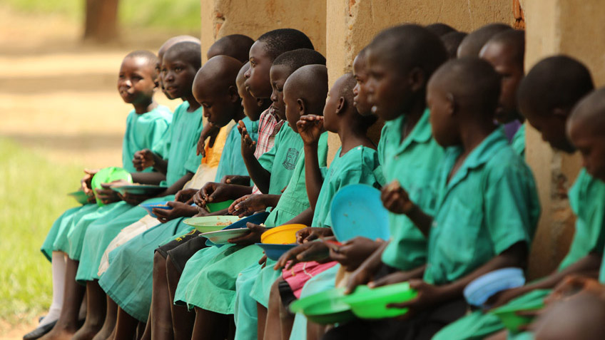 Ugandan school children eating FMSC meals as part of a school feeding program