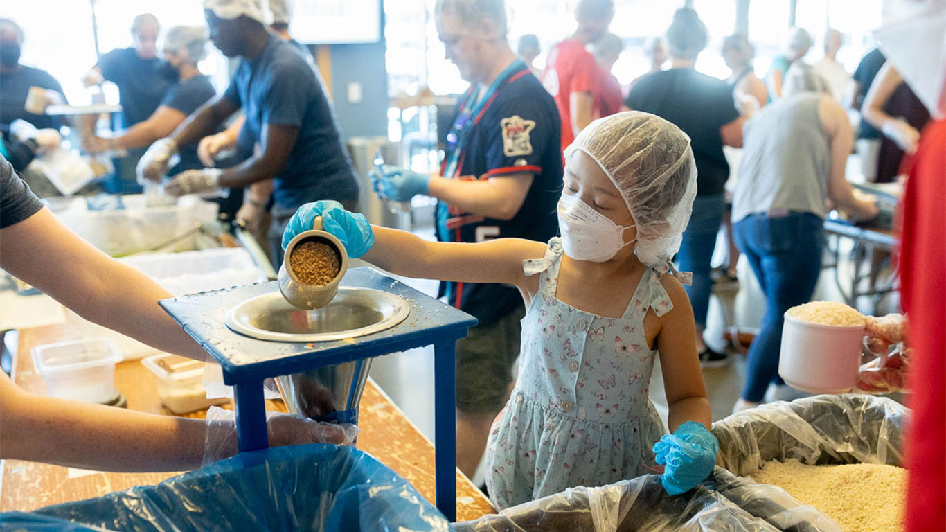 a girl packs meals at FMSC packing event at Target Field