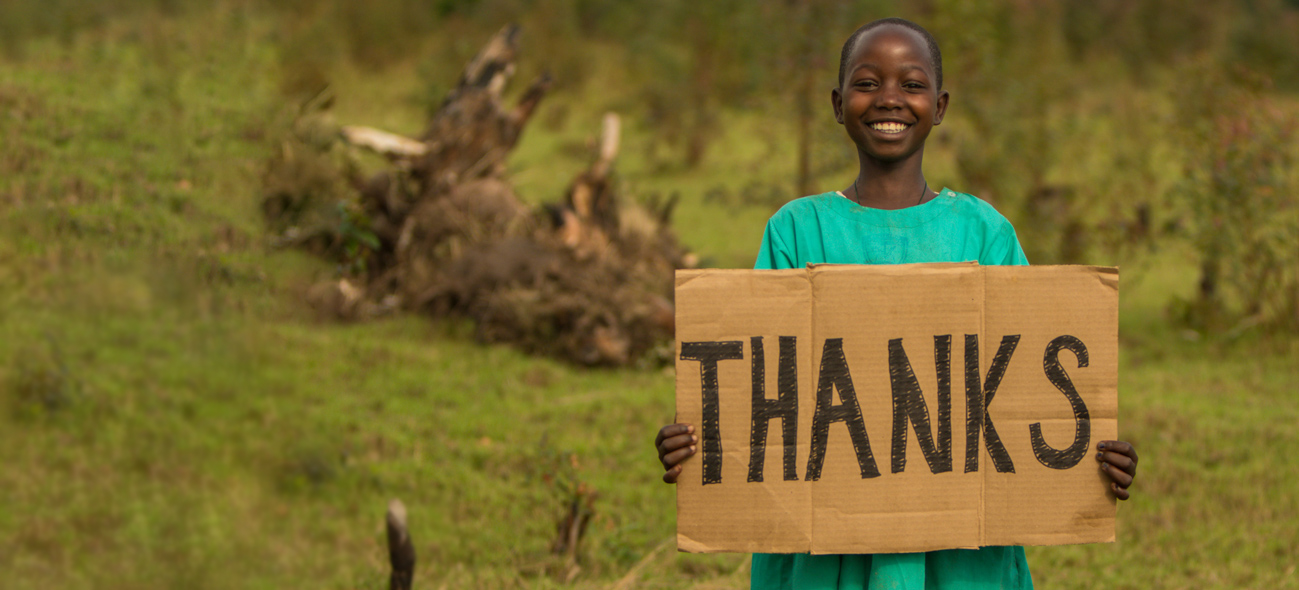 Ugandan child holding a "Thanks" sign